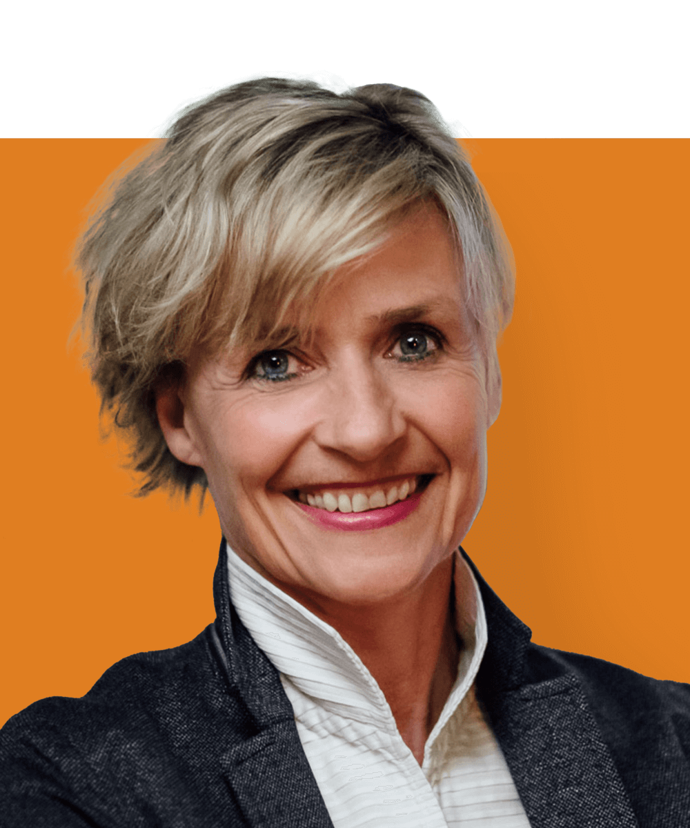 Kopfbild der deutschen Geschäftsführerin Anne Schardey. Sie ist eine kaukasische Frau mit kurzen blonden Haaren und blauen Augen. Sie trägt eine graue Jacke und ein weißes Hemd, während sie in die Kamera lächelt.