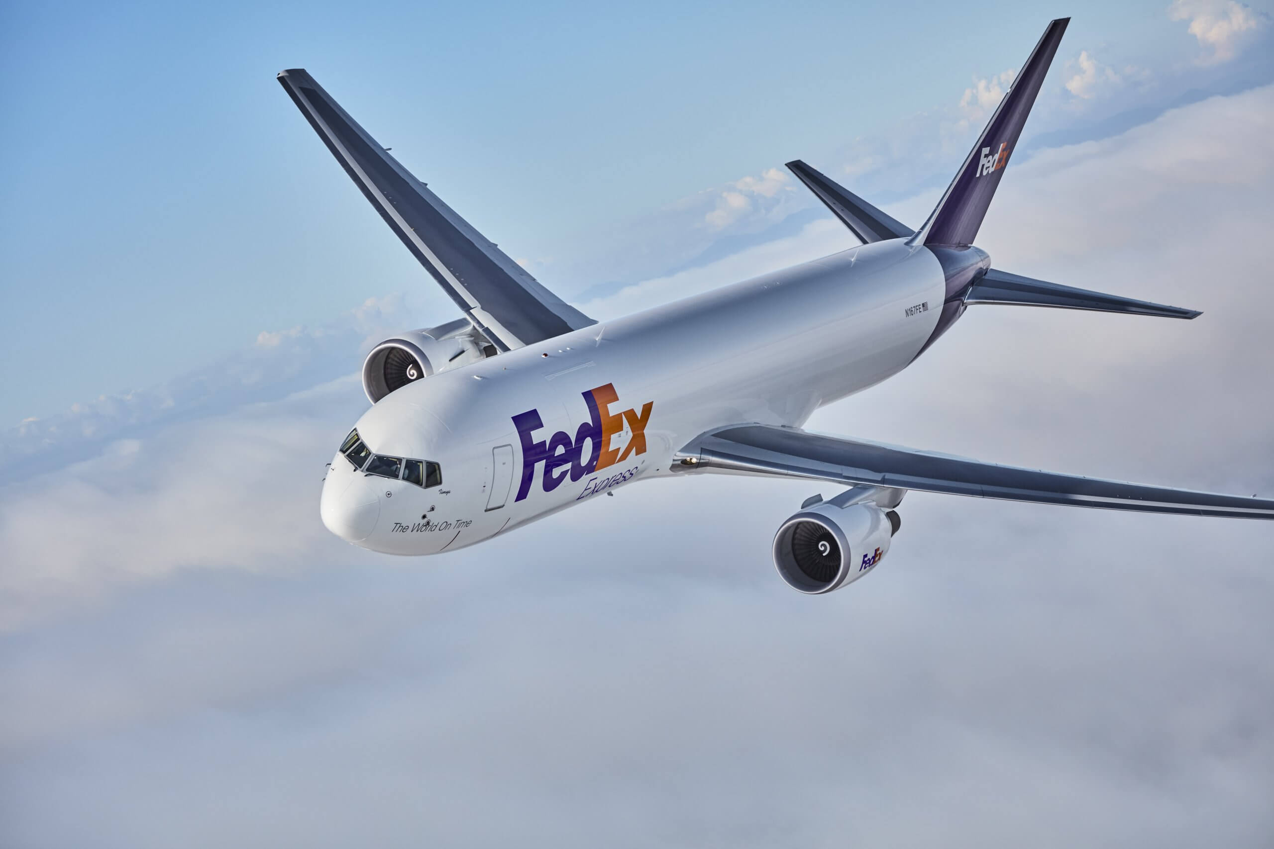 A Fedex plane flying above the clouds.