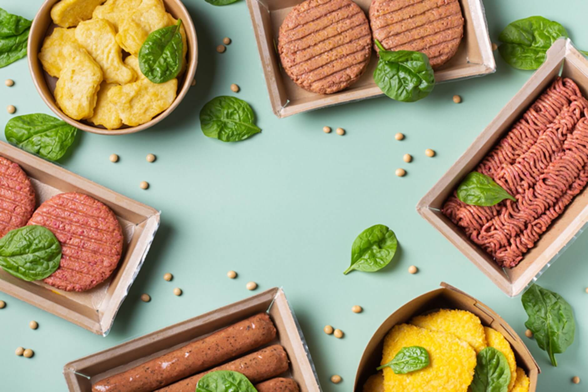 Exemples d'innovations alimentaires comprenant des hamburgers et des saucisses sans viande dans des plats, placés sur un fond vert pâle parsemé de feuilles de basilic.